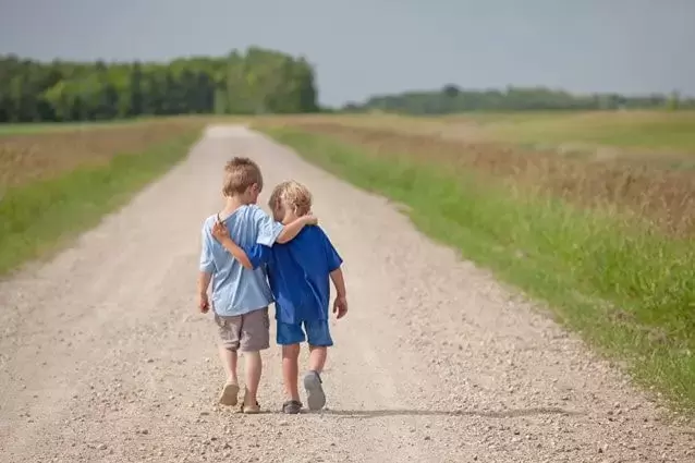Deux enfants se tenant par l'épaule avance sur une route